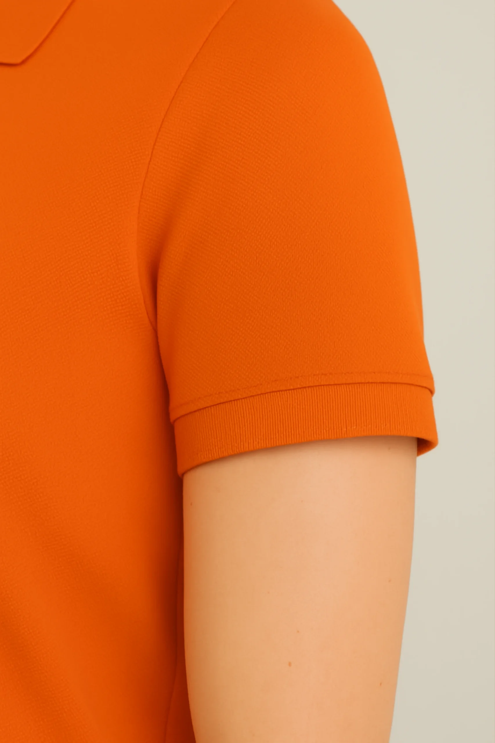 Orange polo t-shirt made from premium cotton blend double piqué fabric with short sleeves, buttoned collar, and regular fit.